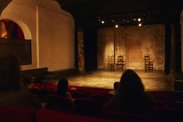 Small flamenco theater in Seville with raked seats facing a lit stage before the show